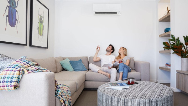 2 people sitting on the couch under a daikin aricon turning it to dry mode